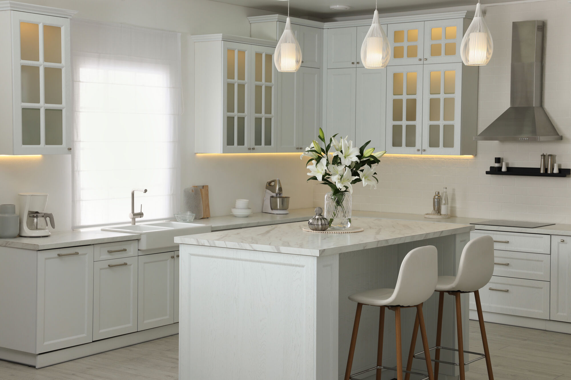 Classic white kitchen with glass-front upper cabinets and a marble island