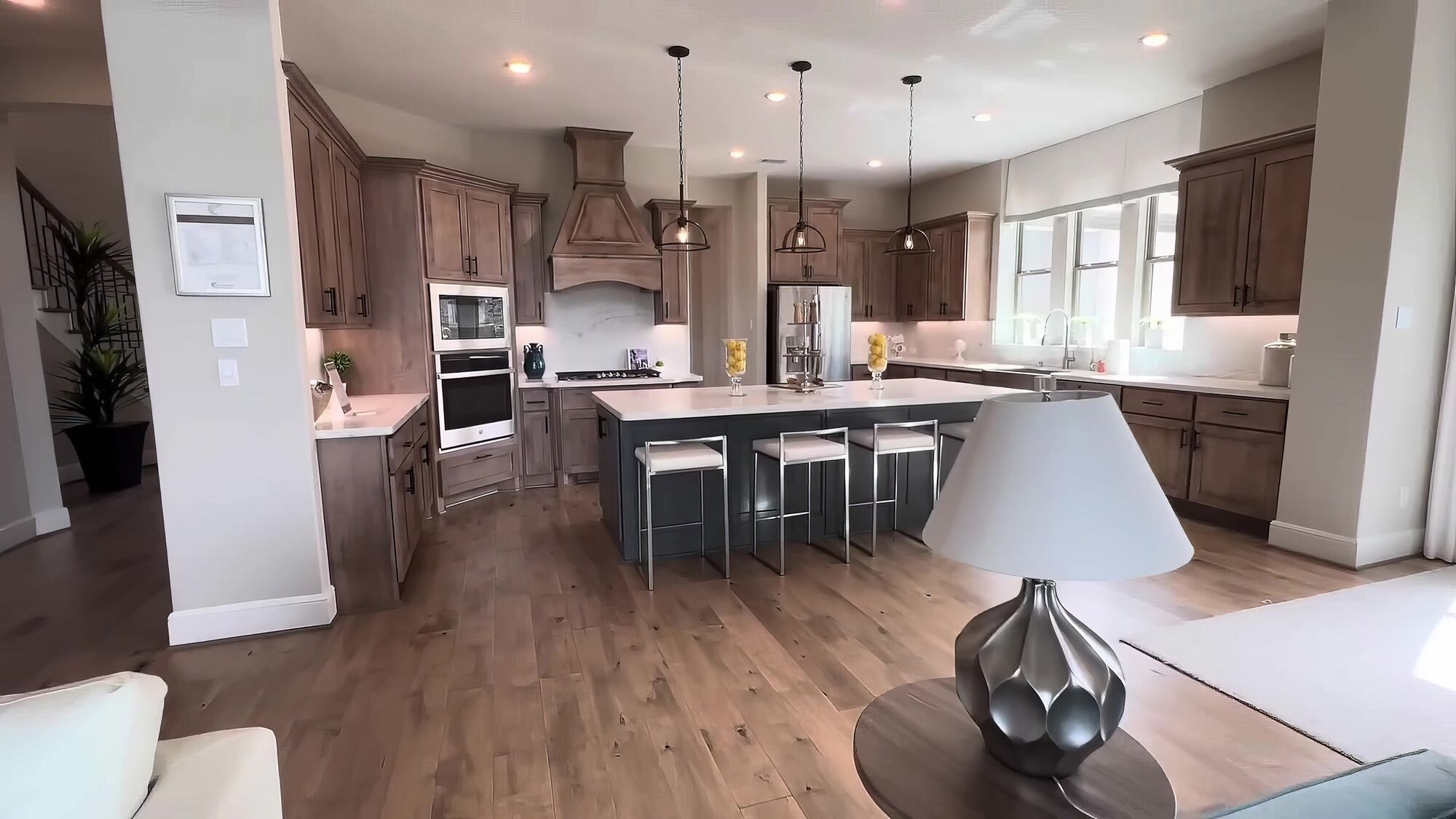 Kitchen with dark wood cabinets, a stone hood and a large island with stools